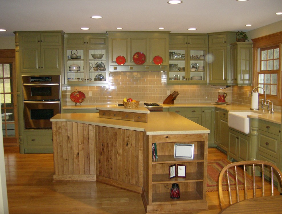 Exempel på ett stort lantligt kök, med en rustik diskho, luckor med infälld panel, gröna skåp, beige stänkskydd, mellanmörkt trägolv och en köksö