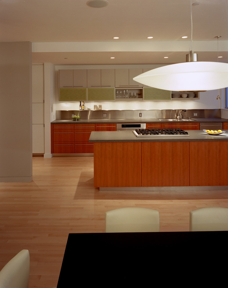 Bild på ett mellanstort funkis linjärt kök med öppen planlösning, med släta luckor, stänkskydd med metallisk yta, en undermonterad diskho, skåp i mellenmörkt trä, granitbänkskiva, rostfria vitvaror, ljust trägolv och en köksö