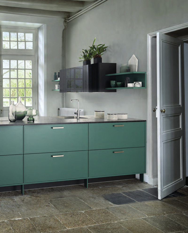 Modern inredning av ett litet kök, med en nedsänkt diskho, gröna skåp, laminatbänkskiva, svarta vitvaror, cementgolv, en köksö och beiget golv