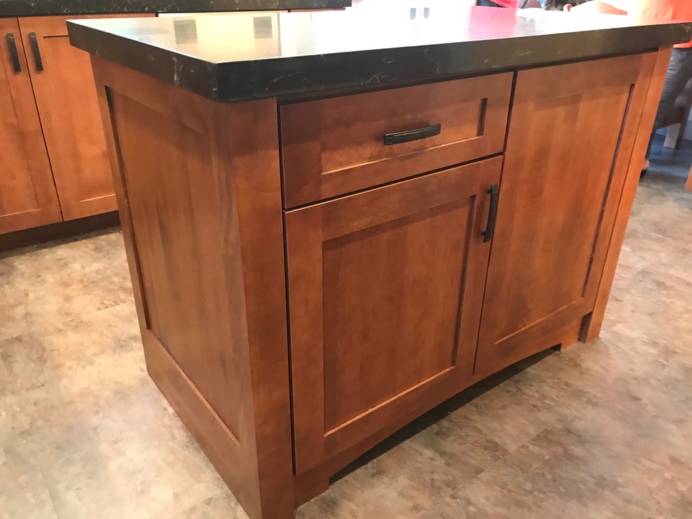 Foto på ett mellanstort amerikanskt svart kök, med en enkel diskho, skåp i shakerstil, skåp i mellenmörkt trä, bänkskiva i kvarts, beige stänkskydd, stänkskydd i stenkakel, rostfria vitvaror, korkgolv, en köksö och flerfärgat golv