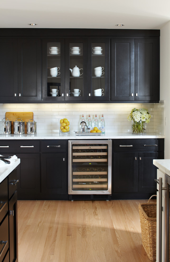 Imagen de cocina clásica renovada con armarios estilo shaker, puertas de armario negras, salpicadero blanco, electrodomésticos de acero inoxidable y suelo de madera clara