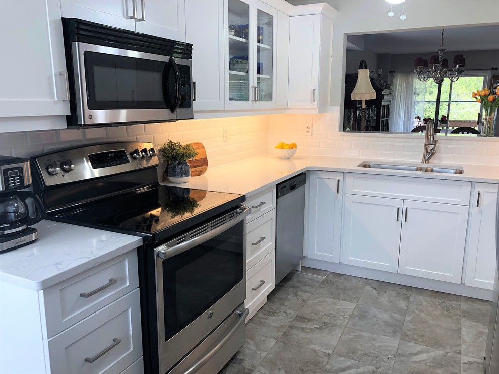 Small trendy u-shaped porcelain tile and beige floor enclosed kitchen photo in Toronto with an undermount sink, shaker cabinets, white cabinets, quartz countertops, white backsplash, ceramic backsplash, stainless steel appliances, no island and white countertops