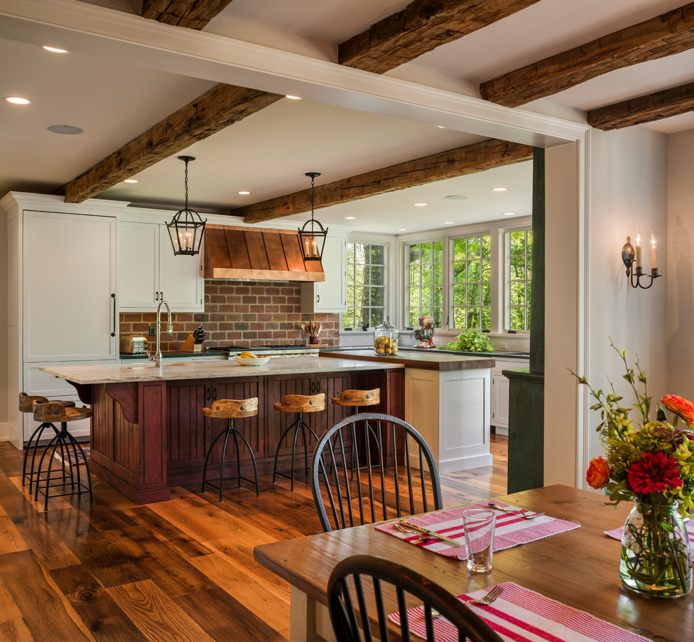 Bild på ett lantligt kök, med luckor med profilerade fronter, vita skåp, marmorbänkskiva, integrerade vitvaror, en köksö och mörkt trägolv