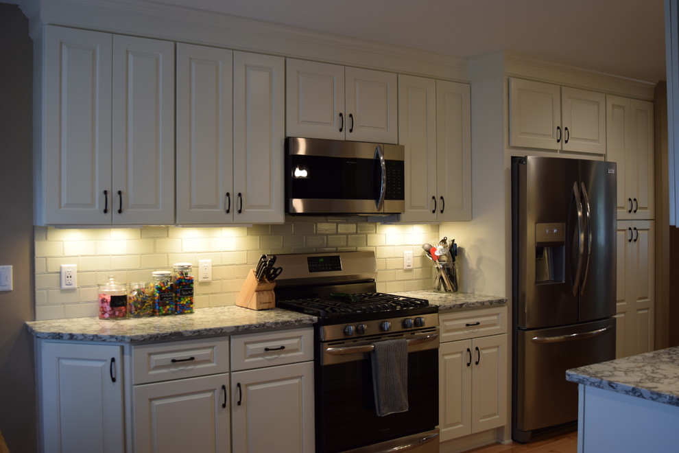 Idées déco pour une cuisine américaine parallèle classique avec des portes de placard blanches, un plan de travail en quartz modifié, un électroménager en acier inoxydable et un plan de travail gris.