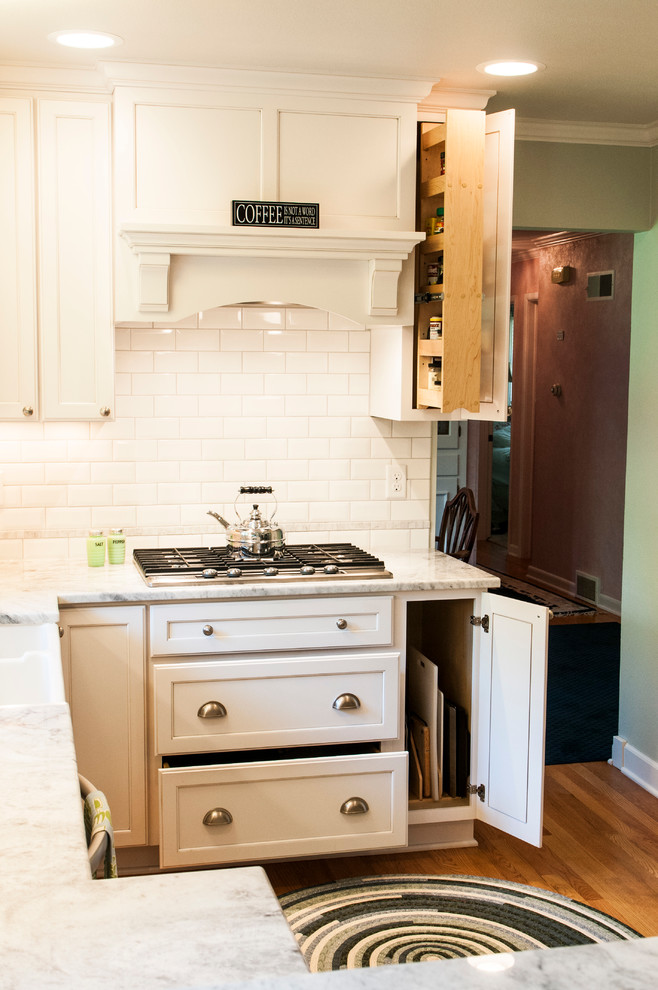 Inredning av ett klassiskt avskilt, litet u-kök, med en rustik diskho, skåp i shakerstil, vita skåp, granitbänkskiva, vitt stänkskydd, stänkskydd i tunnelbanekakel, rostfria vitvaror, mellanmörkt trägolv och en halv köksö