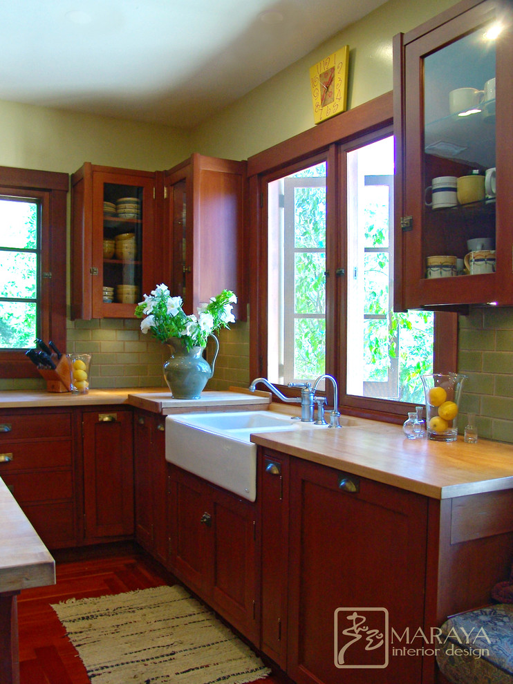 Foto på ett stort amerikanskt kök, med en rustik diskho, luckor med infälld panel, skåp i mellenmörkt trä, träbänkskiva, grönt stänkskydd, stänkskydd i tunnelbanekakel, rostfria vitvaror, mellanmörkt trägolv och en köksö