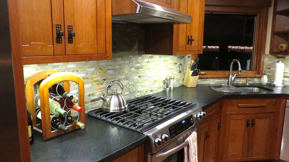 Foto på ett litet amerikanskt kök, med en undermonterad diskho, släta luckor, skåp i mörkt trä, bänkskiva i täljsten, stänkskydd i keramik, rostfria vitvaror, mellanmörkt trägolv och en köksö