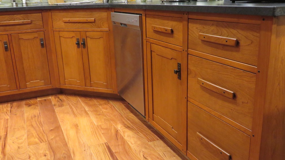 Bild på ett litet amerikanskt kök, med en undermonterad diskho, släta luckor, skåp i mörkt trä, bänkskiva i täljsten, stänkskydd i keramik, rostfria vitvaror, mellanmörkt trägolv och en köksö