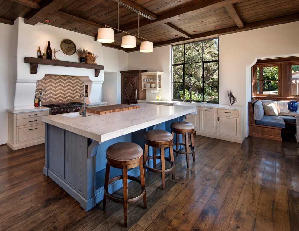 Example of a mid-sized tuscan l-shaped dark wood floor and brown floor kitchen design in Santa Barbara with a farmhouse sink, light wood cabinets, multicolored backsplash, shaker cabinets and an island