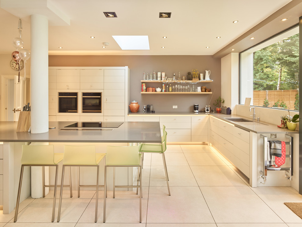 Photo of a medium sized contemporary l-shaped kitchen in West Midlands with a submerged sink, flat-panel cabinets, white cabinets, an island and white floors.