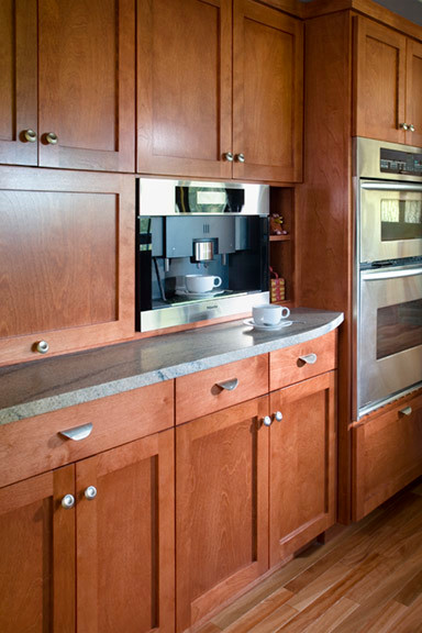 Diseño de cocina actual con electrodomésticos de acero inoxidable y suelo de madera en tonos medios