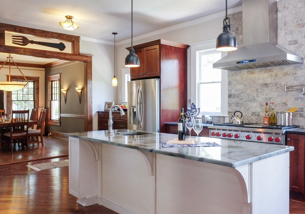 Inspiration for a large timeless l-shaped medium tone wood floor and brown floor eat-in kitchen remodel in Raleigh with an undermount sink, glass countertops, gray backsplash, stone tile backsplash, stainless steel appliances, dark wood cabinets and an island