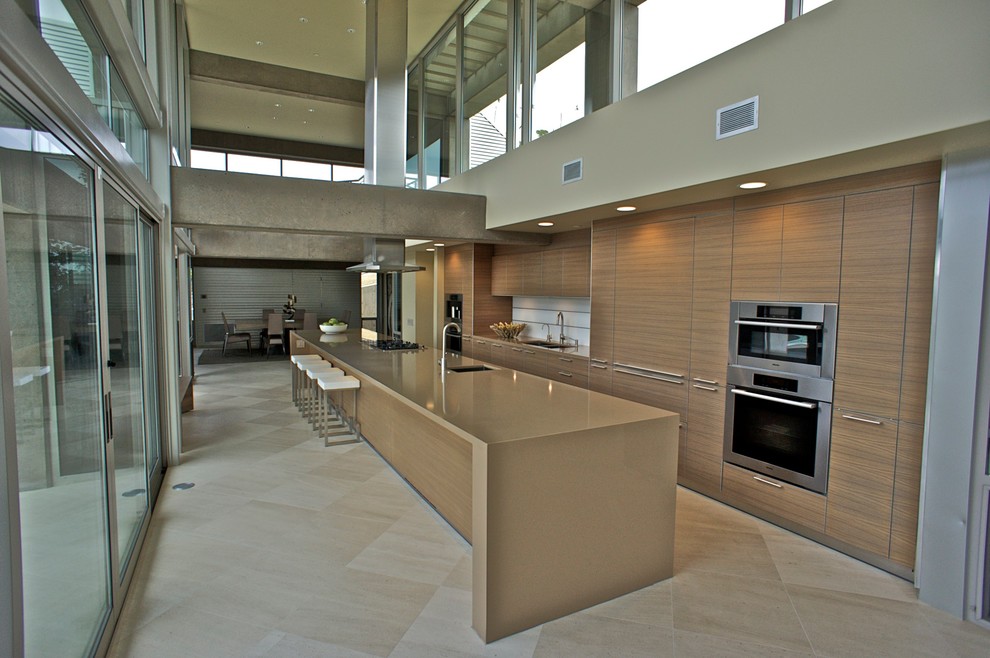 This is an example of a contemporary galley kitchen/diner in Santa Barbara with a submerged sink, flat-panel cabinets, medium wood cabinets, white splashback and stainless steel appliances.