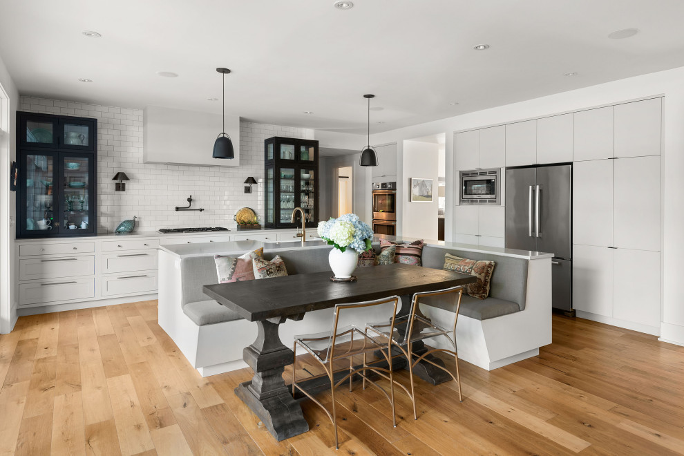 Inspiration for an expansive classic l-shaped kitchen in Orlando with a belfast sink, flat-panel cabinets, grey cabinets, white splashback, metro tiled splashback, medium hardwood flooring, an island, beige floors and white worktops.
