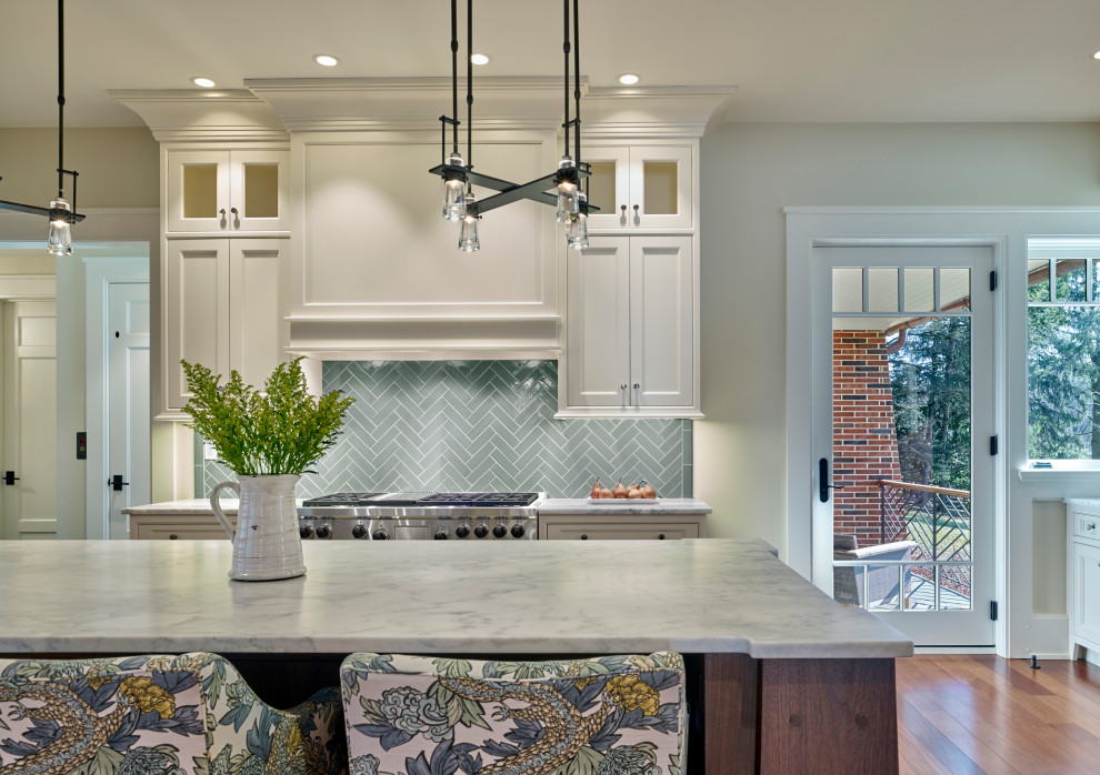 Foto på ett amerikanskt vit kök och matrum, med luckor med infälld panel, vita skåp, marmorbänkskiva, blått stänkskydd, stänkskydd i keramik, rostfria vitvaror, mellanmörkt trägolv och en köksö
