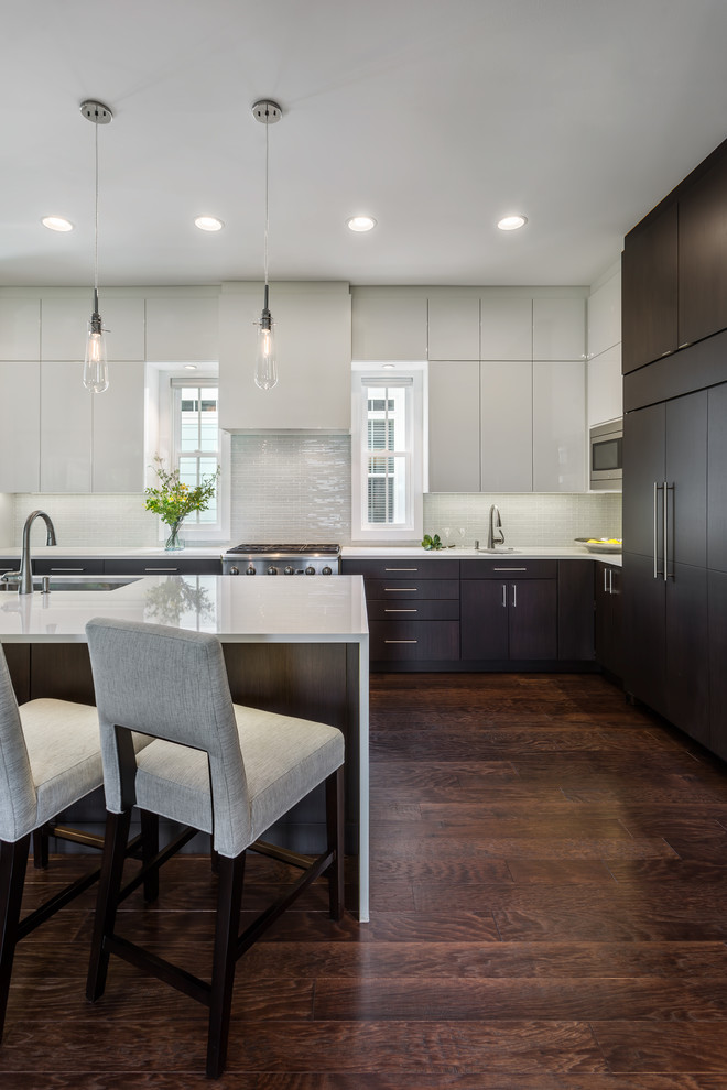 Exempel på ett modernt kök, med en undermonterad diskho, släta luckor, vita skåp, bänkskiva i kvarts, vitt stänkskydd, stänkskydd i keramik, rostfria vitvaror, mörkt trägolv, en köksö och brunt golv