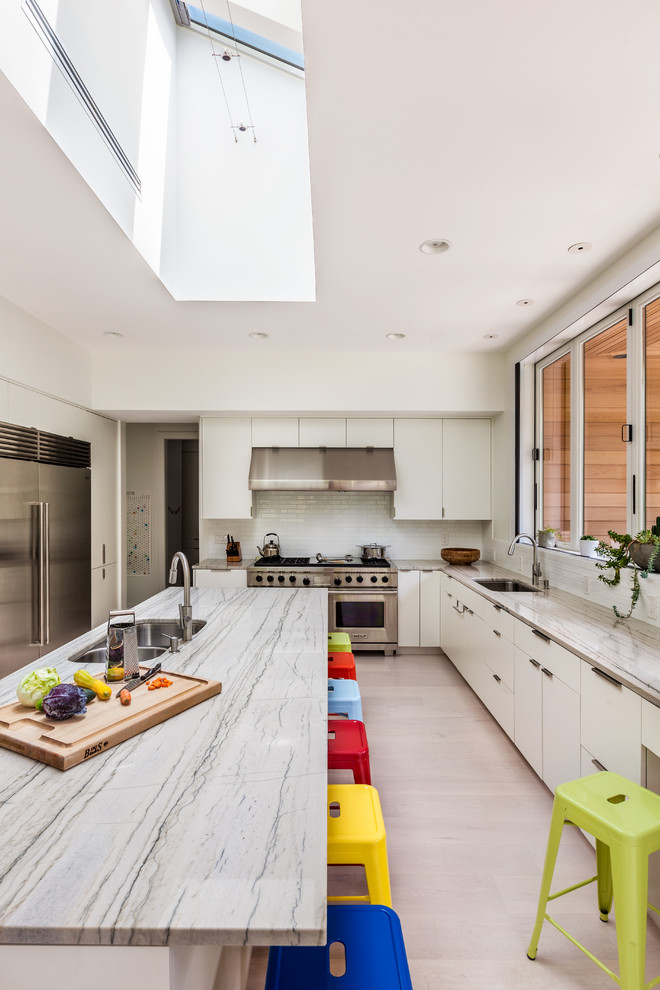 Design ideas for a large contemporary u-shaped open plan kitchen in Charleston with a submerged sink, flat-panel cabinets, white cabinets, white splashback, metro tiled splashback, stainless steel appliances and an island.