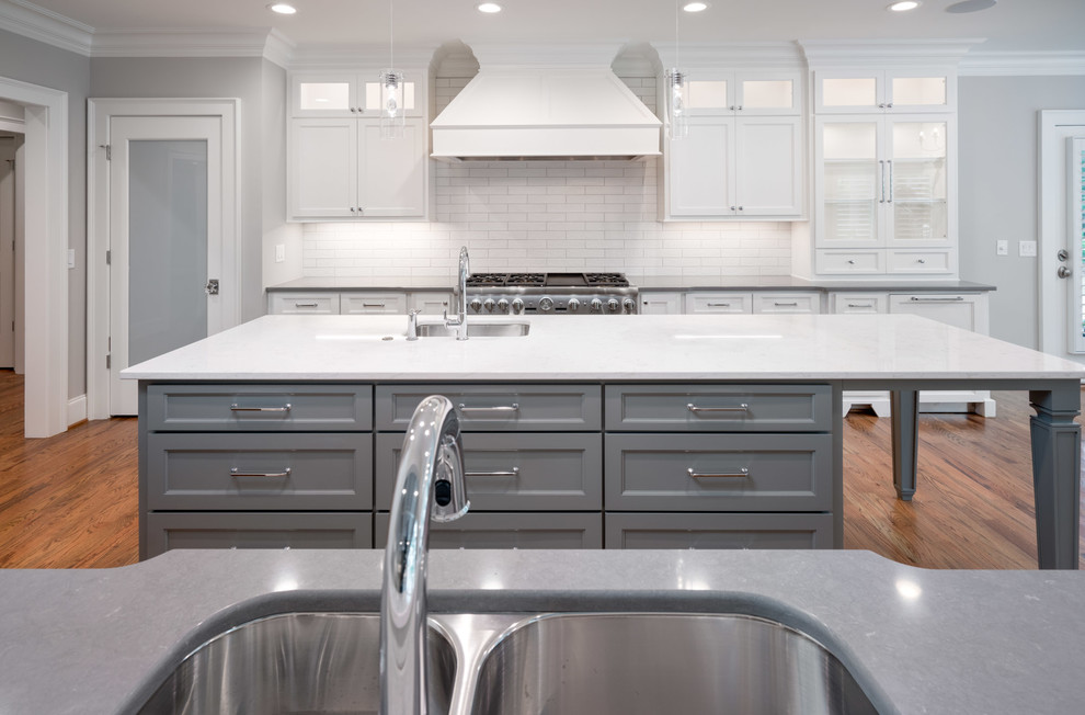 Inspiration for a large transitional u-shaped medium tone wood floor and brown floor eat-in kitchen remodel in Other with an undermount sink, shaker cabinets, white cabinets, quartz countertops, white backsplash, subway tile backsplash, stainless steel appliances and an island