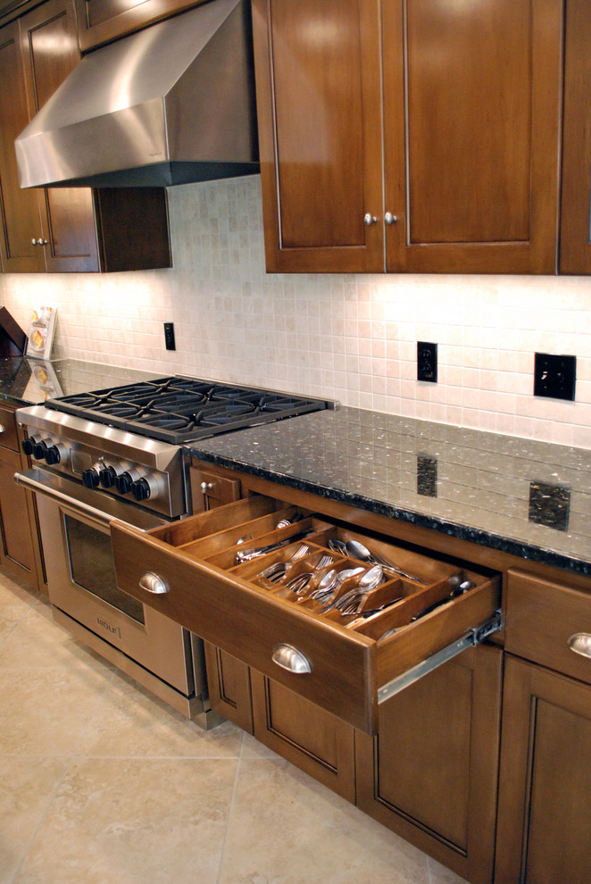 This is an example of a large traditional galley kitchen/diner in Dallas with a built-in sink, recessed-panel cabinets, dark wood cabinets, granite worktops, beige splashback, ceramic splashback, stainless steel appliances, ceramic flooring and an island.