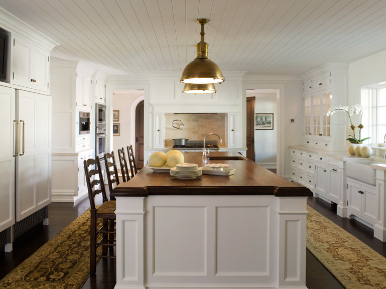 Example of a classic u-shaped enclosed kitchen design in Los Angeles with a farmhouse sink, beaded inset cabinets, white cabinets, beige backsplash, stone slab backsplash and stainless steel appliances