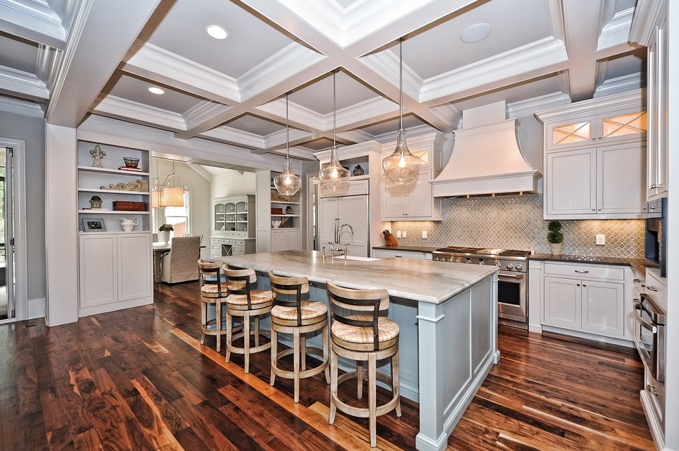 Large arts and crafts l-shaped dark wood floor open concept kitchen photo in Charlotte with shaker cabinets, white cabinets, white appliances, an island, a farmhouse sink, quartzite countertops, gray backsplash and ceramic backsplash