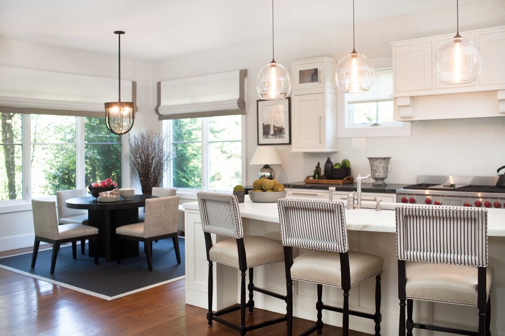 Inspiration for a large transitional galley medium tone wood floor eat-in kitchen remodel in New York with an undermount sink, shaker cabinets, white cabinets, marble countertops, white backsplash, stainless steel appliances and an island