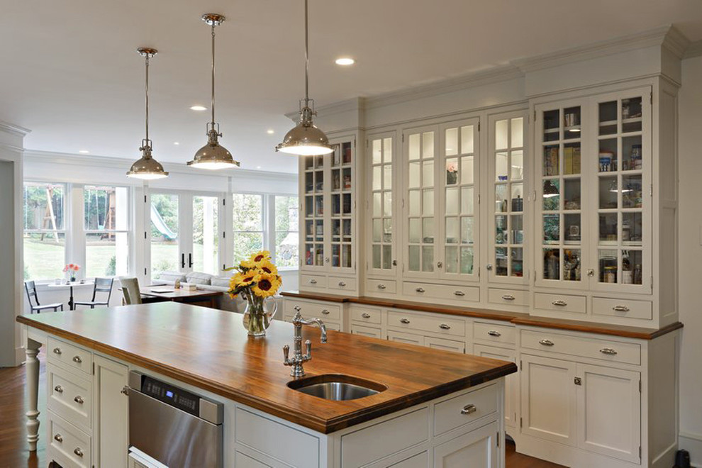 Large elegant u-shaped light wood floor enclosed kitchen photo in New York with a double-bowl sink, recessed-panel cabinets, beige cabinets, wood countertops, an island and beige countertops