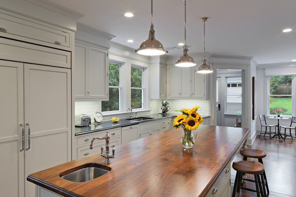 Example of a large classic u-shaped light wood floor enclosed kitchen design in New York with a double-bowl sink, recessed-panel cabinets, wood countertops, an island and beige countertops