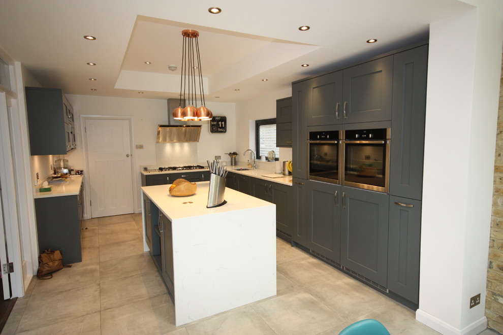 This is an example of an expansive contemporary kitchen/diner in London with shaker cabinets, grey cabinets, quartz worktops, integrated appliances, porcelain flooring, an island and multi-coloured floors.