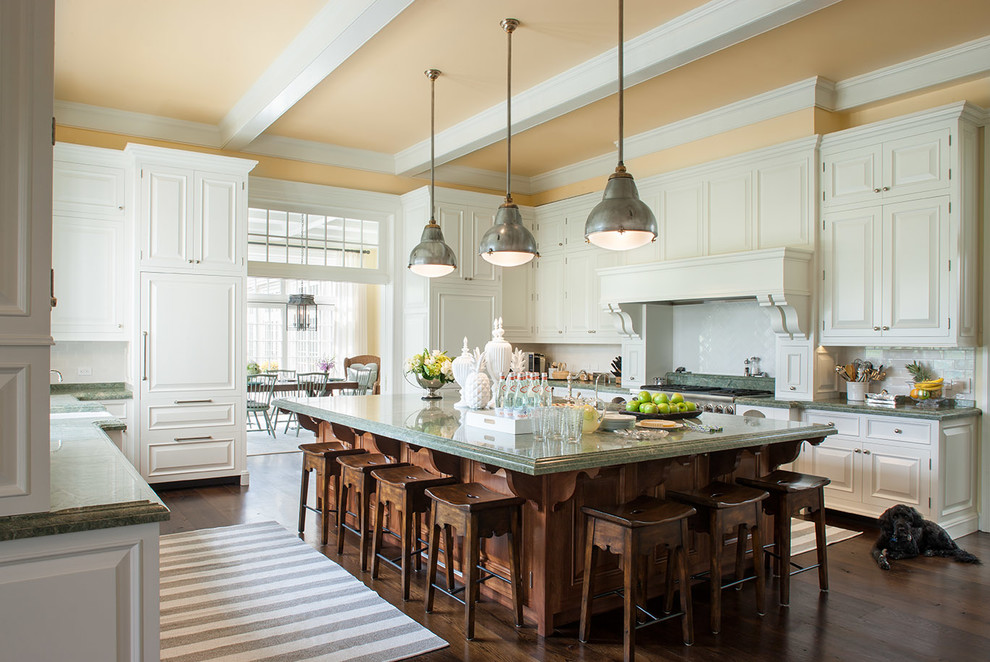 Foto di un grande cucina con isola centrale tradizionale chiuso con ante bianche, top in granito, paraspruzzi bianco, paraspruzzi con piastrelle in ceramica, parquet scuro, top verde, ante con bugna sagomata e pavimento marrone