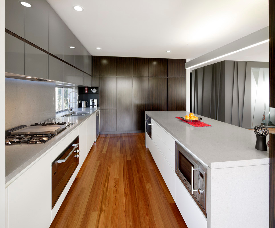 Photo of a medium sized contemporary l-shaped kitchen/diner in Sydney with a submerged sink, glass-front cabinets, engineered stone countertops, stone slab splashback, dark wood cabinets, grey splashback, stainless steel appliances, medium hardwood flooring and an island.