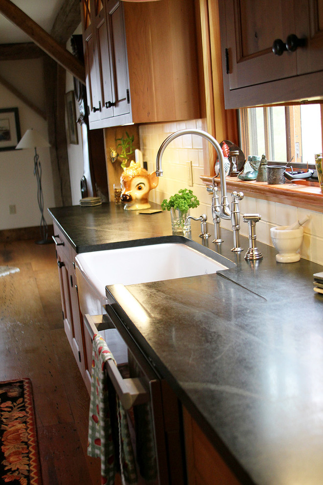 Bild på ett stort lantligt kök, med en rustik diskho, luckor med infälld panel, skåp i mellenmörkt trä, bänkskiva i täljsten, rostfria vitvaror och en köksö