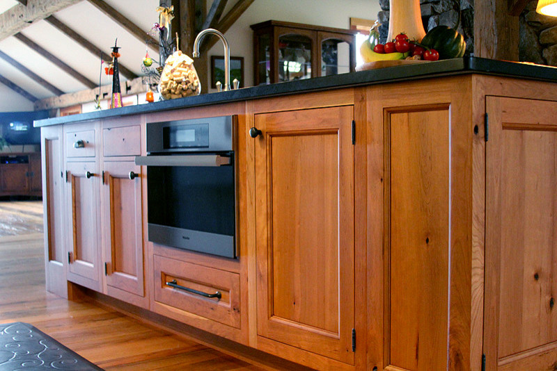 Example of a large farmhouse l-shaped open concept kitchen design in Boston with a farmhouse sink, recessed-panel cabinets, medium tone wood cabinets, soapstone countertops, stainless steel appliances and an island