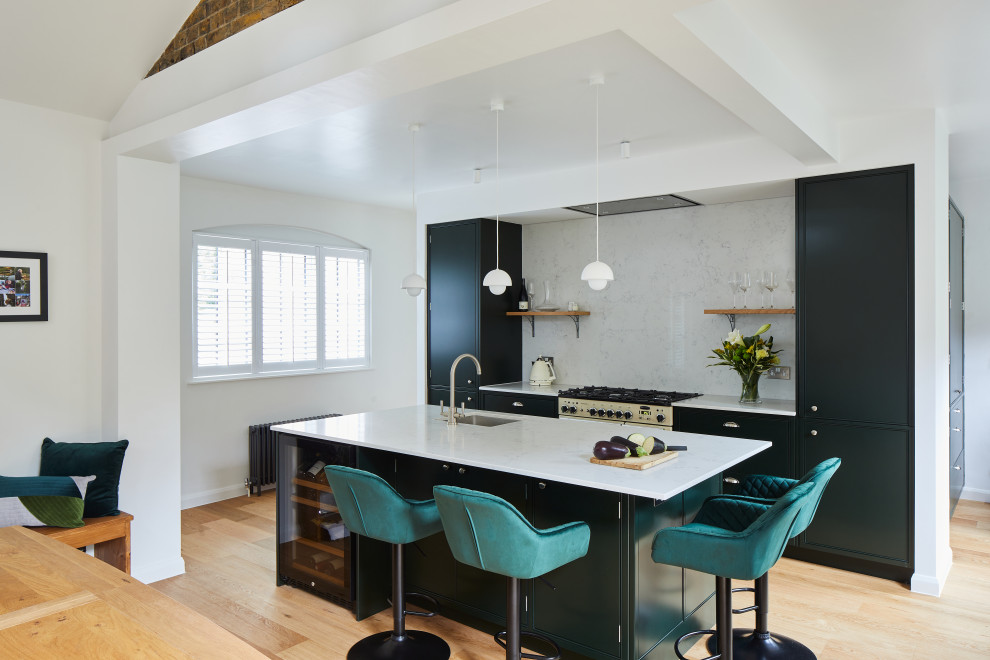 Example of a mid-sized trendy galley light wood floor, brown floor and vaulted ceiling eat-in kitchen design in London with an undermount sink, flat-panel cabinets, green cabinets, quartzite countertops, gray backsplash, quartz backsplash, colored appliances, an island and gray countertops