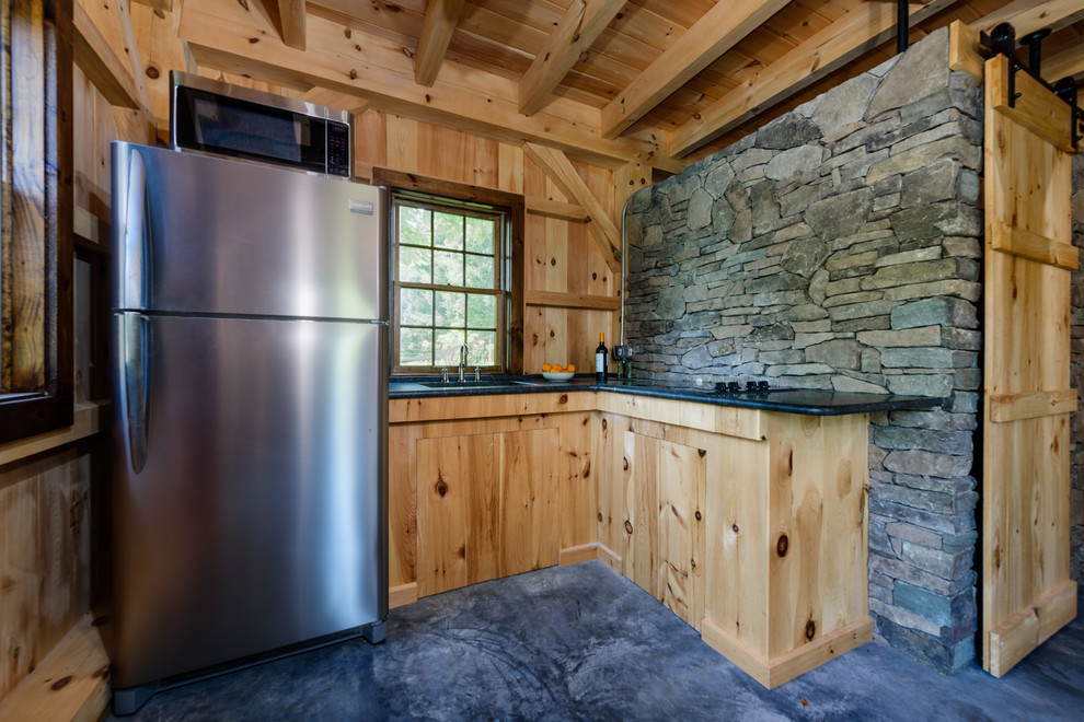 Rustik inredning av ett litet brun brunt u-kök, med en undermonterad diskho, släta luckor, skåp i ljust trä, granitbänkskiva, stänkskydd i skiffer, betonggolv och grått golv