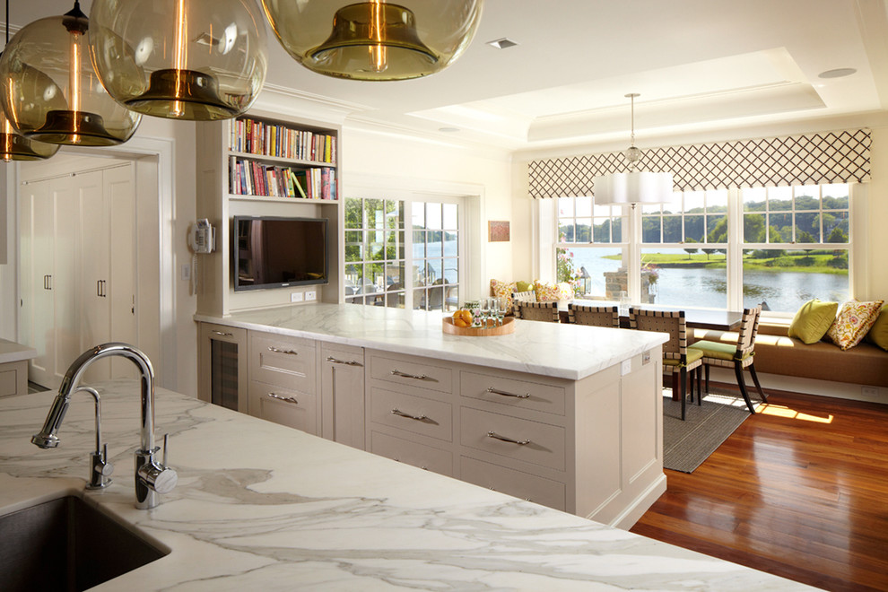 Inspiration for an expansive classic galley kitchen/diner in New York with a submerged sink, white cabinets, marble worktops, stainless steel appliances, medium hardwood flooring and an island.