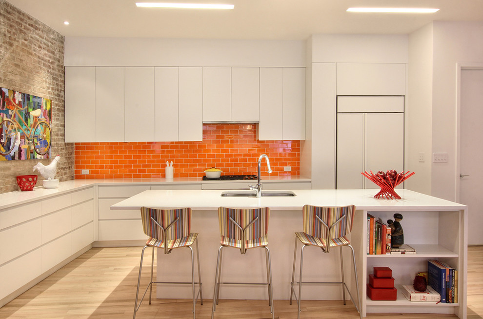 This is an example of a medium sized contemporary l-shaped kitchen in New York with a submerged sink, flat-panel cabinets, white cabinets, orange splashback, metro tiled splashback, integrated appliances, light hardwood flooring, an island and quartz worktops.