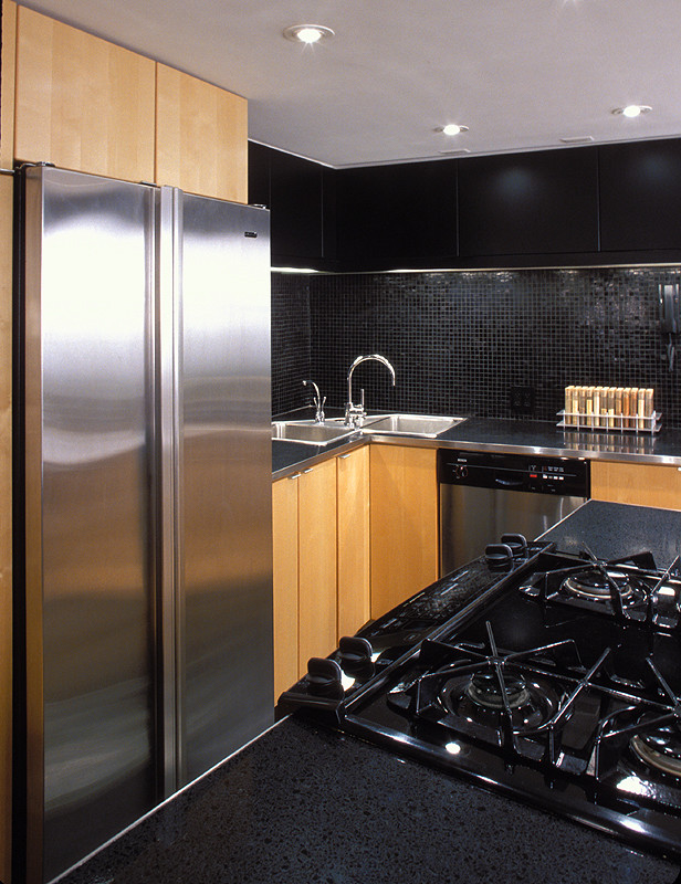 Moderne Küche mit Küchenrückwand in Schwarz, flächenbündigen Schrankfronten, hellen Holzschränken, Edelstahl-Arbeitsplatte und Küchengeräten aus Edelstahl in New York