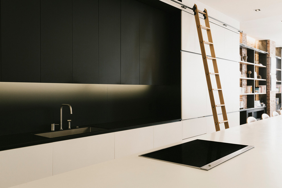 Foto di una grande cucina contemporanea chiusa con paraspruzzi nero, lavello sottopiano, ante lisce, ante bianche, top in superficie solida, elettrodomestici bianchi e pavimento in legno massello medio