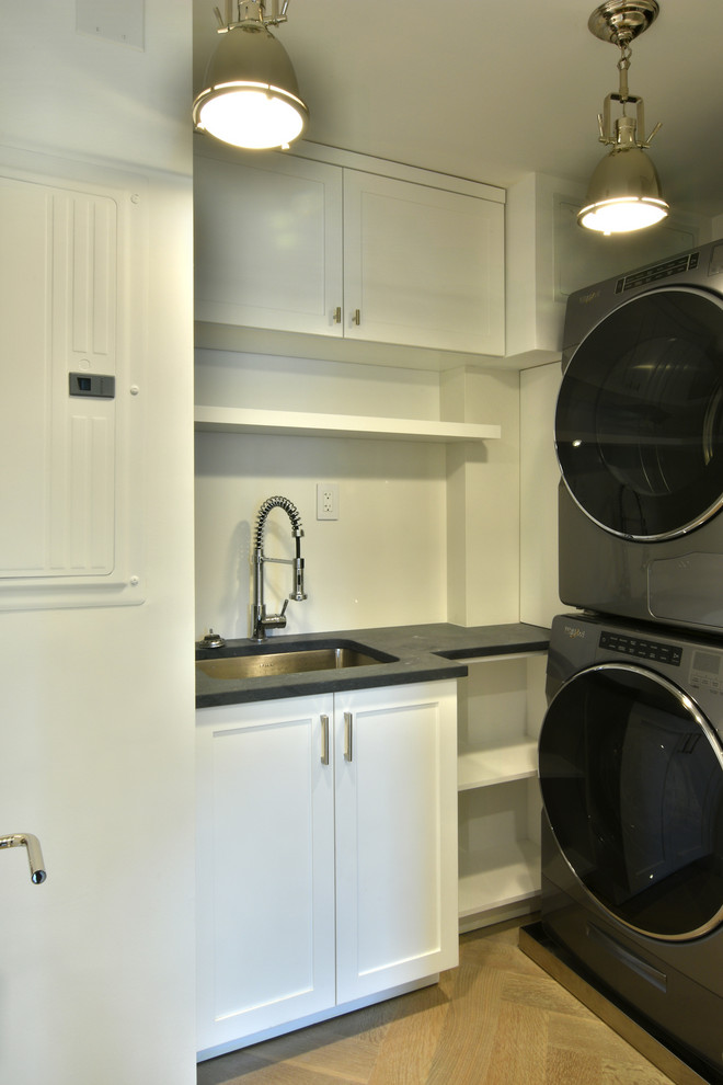 Photo of a small traditional galley utility room in New York with a submerged sink, shaker cabinets, white cabinets, marble worktops, white splashback, stone slab splashback, light hardwood flooring, beige floors and white worktops.