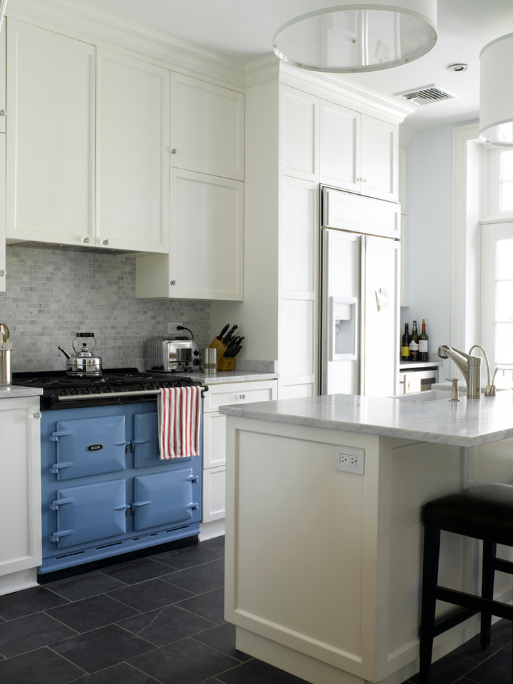 Mid-sized transitional galley slate floor enclosed kitchen photo in New York with a farmhouse sink, beaded inset cabinets, white cabinets, marble countertops, gray backsplash, mosaic tile backsplash, stainless steel appliances and an island