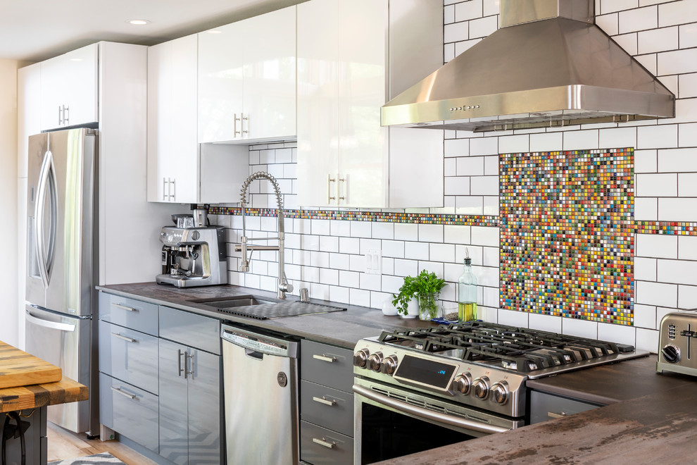 Industrial grey and white kitchen in Seattle with a submerged sink, flat-panel cabinets, grey cabinets, multi-coloured splashback, mosaic tiled splashback, stainless steel appliances and brown worktops.