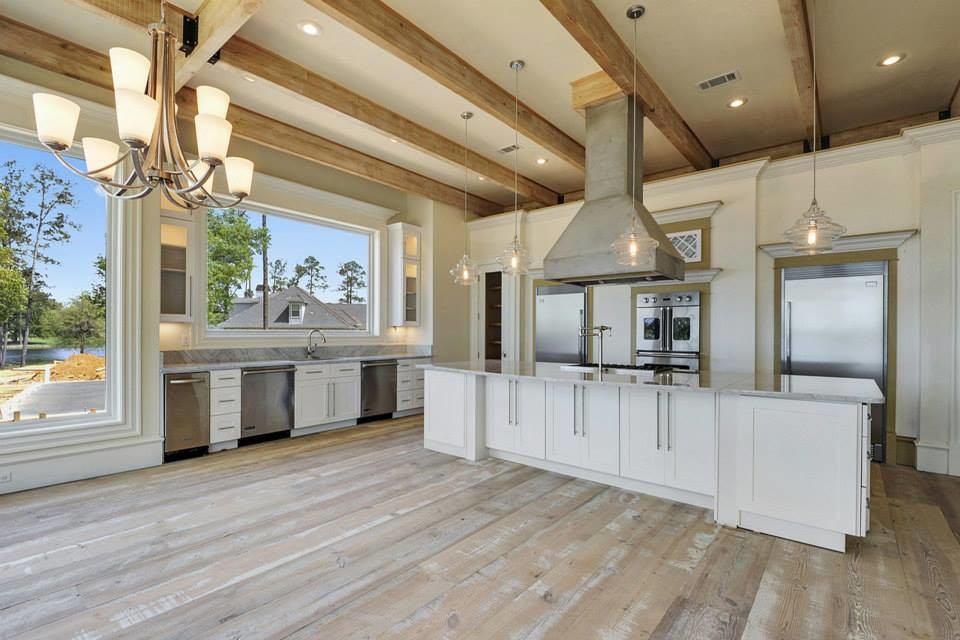 Large elegant galley medium tone wood floor and brown floor open concept kitchen photo in New Orleans with an undermount sink, recessed-panel cabinets, white cabinets, granite countertops, stainless steel appliances and an island