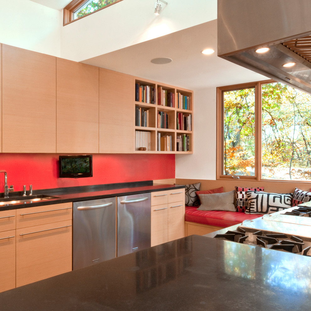 Immagine di una cucina design con lavello sottopiano, ante lisce, ante in legno chiaro, elettrodomestici in acciaio inossidabile e paraspruzzi rosso