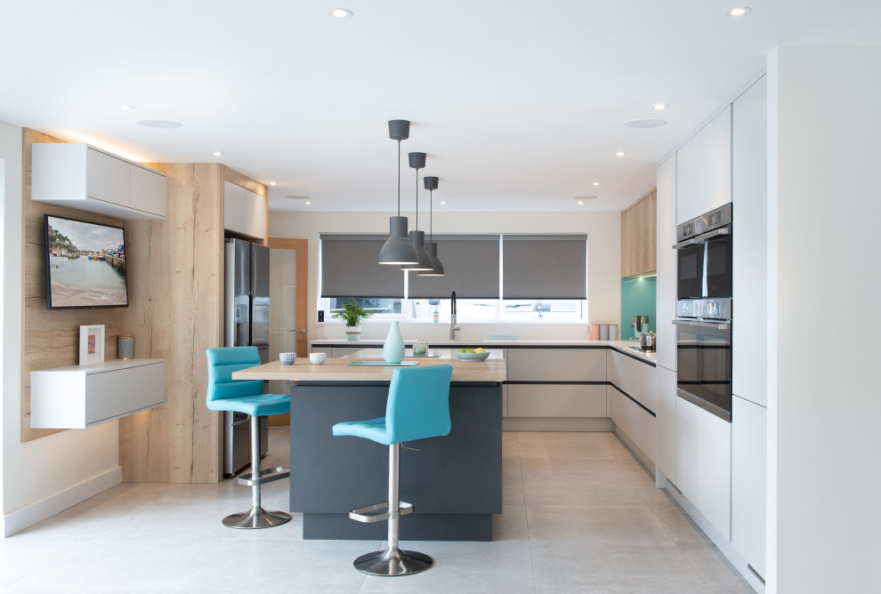 Inspiration for a large contemporary u-shaped open plan kitchen in Cornwall with flat-panel cabinets, grey cabinets, quartz worktops, glass sheet splashback, ceramic flooring, an island, white worktops, stainless steel appliances and grey floors.