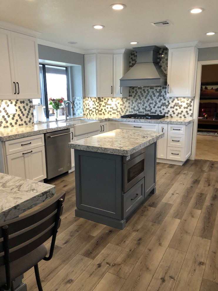 Large traditional u-shaped open plan kitchen in Los Angeles with a belfast sink, shaker cabinets, white cabinets, engineered stone countertops, multi-coloured splashback, mosaic tiled splashback, stainless steel appliances, vinyl flooring, multiple islands, grey floors and grey worktops.