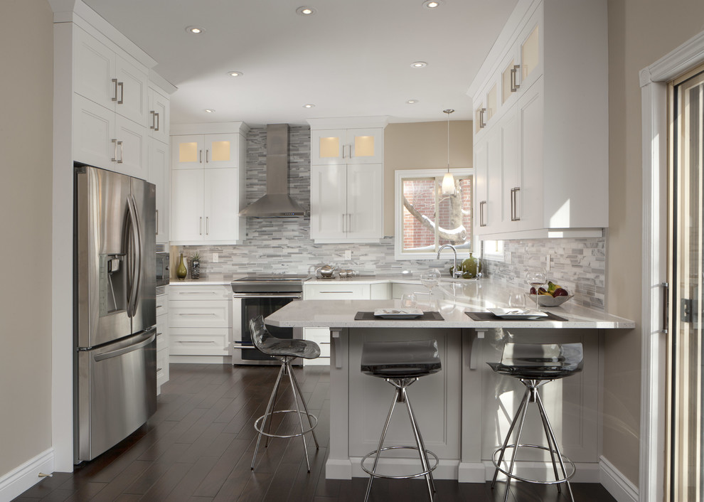 Exempel på ett avskilt, litet klassiskt l-kök, med en undermonterad diskho, skåp i shakerstil, vita skåp, bänkskiva i kvarts, grått stänkskydd, mörkt trägolv, en halv köksö, stänkskydd i stickkakel, rostfria vitvaror och brunt golv