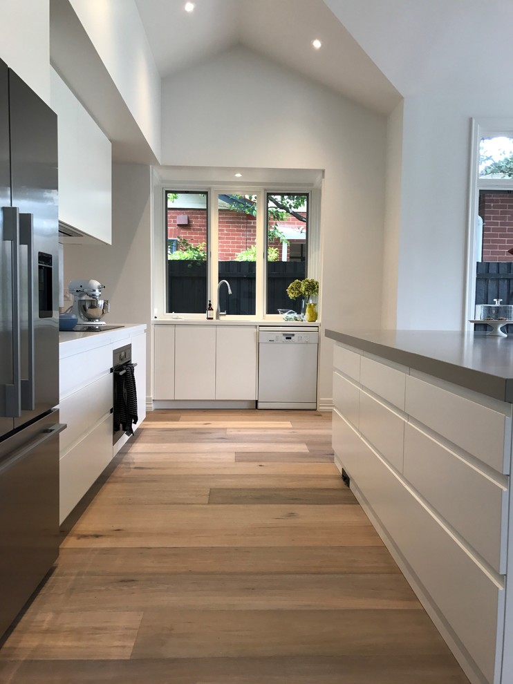 Inspiration for a large modern galley light wood floor eat-in kitchen remodel in Sydney with an undermount sink, recessed-panel cabinets, white cabinets, quartz countertops, white backsplash, stone slab backsplash, stainless steel appliances and an island