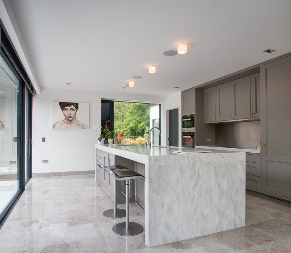 Exempel på ett stort modernt linjärt kök och matrum, med en undermonterad diskho, luckor med infälld panel, grå skåp, bänkskiva i koppar, grått stänkskydd, glaspanel som stänkskydd, integrerade vitvaror, marmorgolv, en köksö och grått golv
