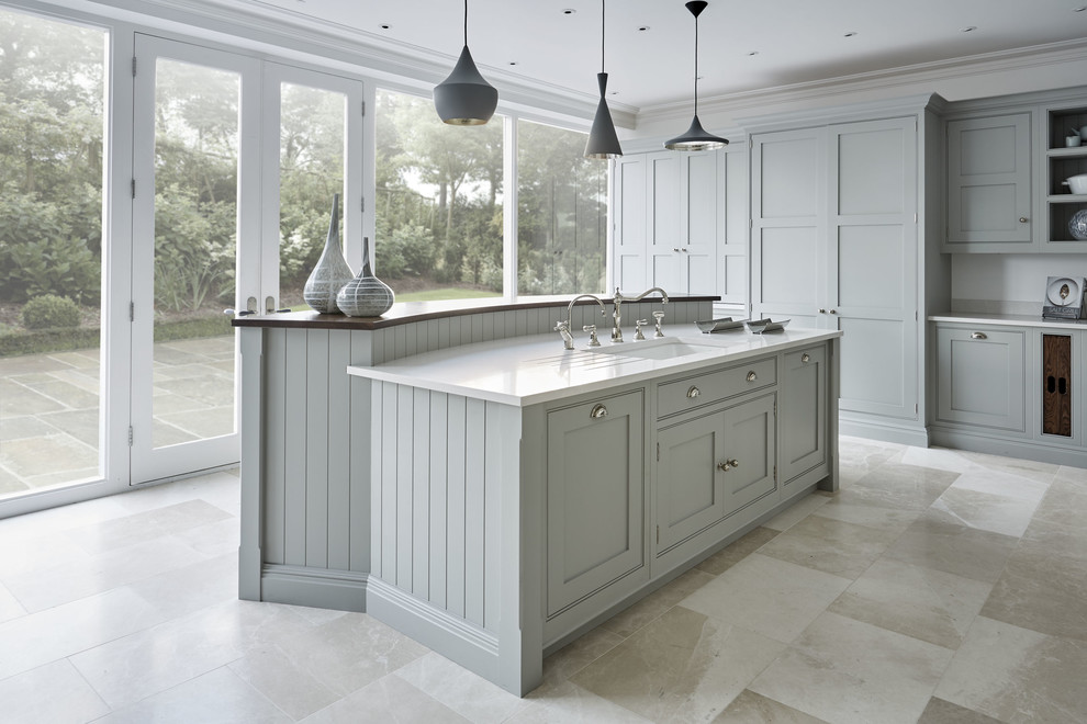 Large contemporary u-shaped kitchen/diner in Kent with a belfast sink, shaker cabinets, grey cabinets, quartz worktops, white splashback, stainless steel appliances, marble flooring, an island and beige floors.